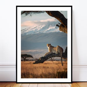 Puede incluir: Impresión enmarcada de un guepardo descansando en una rama. El felino moteado se encuentra frente a un paisaje de montañas y sabana dorada. El cielo muestra tonos azules y rosados, creando una escena pintoresca.
