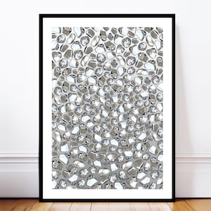 May include: Framed artwork showing a close-up of a pattern of irregularly shaped, reflective, silver-toned stones. The stones are set against a light grey background, creating a textured and shimmering effect. The artwork is encased in a black frame.