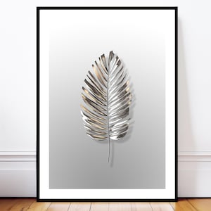 Puede incluir: Impresión enmarcada con una hoja de palmera metálica plateada y dorada sobre un fondo gris degradado. La hoja tiene vetas texturizadas y un tallo oscuro. La obra de arte se muestra en un marco negro.