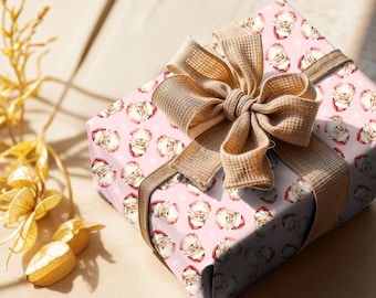May include: A wrapped gift box featuring pink wrapping paper with a repeating Santa Claus pattern and white snowflakes. The box is tied with a large, textured tan bow and matching ribbon, perfect for Christmas.