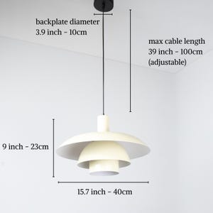 May include: Cream-colored pendant light with a layered design. The backplate diameter is 3.9 inches (10cm), the height is 9 inches (23cm), and the width is 15.7 inches (40cm). The max cable length is 39 inches (100cm).