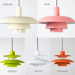 May include: A collection of pendant lights in various colors: cream, pink, green, white, and orange. Each light has a tiered, saucer-like shade design and a black cord. The colors are labeled in the image.