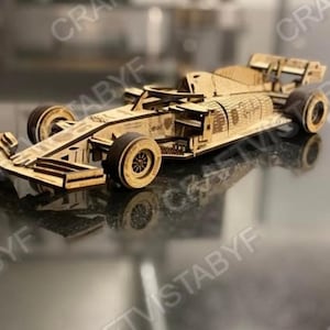 Può includere: Un modello in legno di un'auto da corsa di Formula 1. Il modello è realizzato in legno chiaro con pneumatici marrone scuro e dettagli intricati. L'auto è una replica di un veicolo di Formula 1.