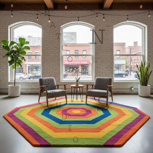 Könnte beinhalten: Ein farbenfroher, geometrischer Teppich mit einem Regenbogen aus Farben, darunter Orange, Gelb, Grün und Lila. Der Raum hat zwei graue Sessel, einen kleinen Tisch und große Fenster. Der Raum hat ein modernes, minimalistisches Design.