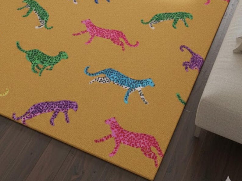 May include: Mustard-colored rug featuring a repeating pattern of colorful cheetahs. The cheetahs are in shades of pink, purple, blue, and green, with a speckled design. The rug is rectangular and appears to be made of a soft material.