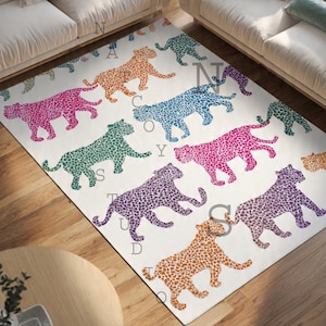 May include: A rectangular area rug with a repeating pattern of colorful leopard silhouettes in orange, pink, purple, blue, and green on a white background. The rug is placed on a wooden floor, with a round table and a sofa visible.