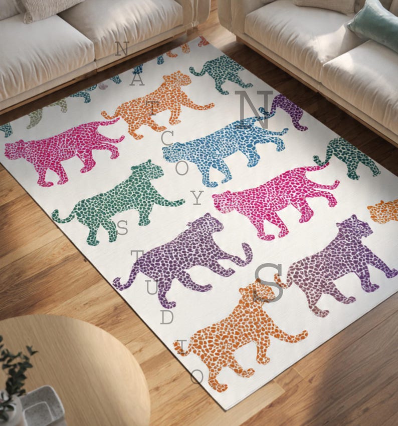 May include: A rectangular area rug with a repeating pattern of colorful leopard silhouettes in orange, pink, purple, blue, and green on a white background. The rug is placed on a wooden floor, with a round table and a sofa visible.