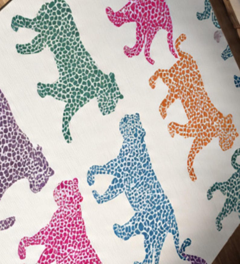 May include: A repeating pattern of stylized leopards in various colors, including green, pink, orange, blue, and purple, against a white background. The leopards are depicted with a spotted texture, creating a playful and vibrant design.