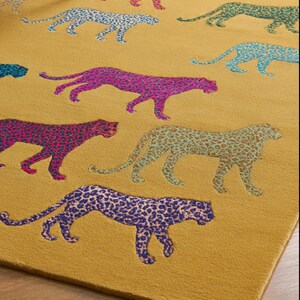 Puede incluir: Alfombra de color amarillo mostaza con un patr&oacute;n repetido de leopardos estilizados en varios colores, incluyendo rosa, azul y verde. El dise&ntilde;o de estampado de leopardo a&ntilde;ade un toque l&uacute;dico y moderno. La alfombra es un elemento decorativo para el hogar.