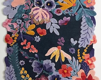 May include: A floral rug with a dark background and a variety of colorful flowers. The rug features a mix of pink, purple, yellow, and orange flowers, with green leaves. The rug has a scalloped edge.