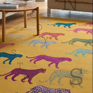 Puede incluir: Alfombra de color amarillo mostaza con un patr&oacute;n repetido de figuras de leopardo de colores. Los leopardos son en tonos de azul, rosa, morado y verde. La alfombra est&aacute; en un sal&oacute;n.