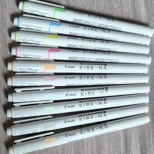 Peut inclure: Plusieurs surligneurs Pilot Kire-Na de couleurs variées, dont vert, bleu, jaune, rose et orange. Chaque surligneur a un corps blanc avec le nom de la marque et du produit imprimé. Les pointes sont codées par couleur.