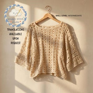 May include: A cream-coloured crochet top with a wide neckline and three-quarter length sleeves, featuring an intricate openwork pattern. The image includes the text "SKILL LEVEL: INTERMEDIATE" and "TRANSLATIONS AVAILABLE UPON REQUEST" with a logo.