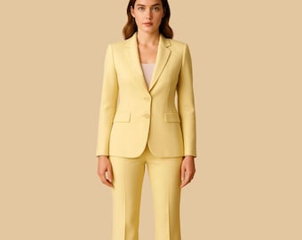 May include: A light yellow women's suit, featuring a tailored blazer with two front pockets and matching flared trousers. The suit is made of a smooth fabric and is buttoned at the front. The background is a solid beige color.