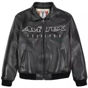 May include: Black leather jacket with the white text "Avi Rex" and "Trapstar" across the chest. The jacket has a collared neckline, a zipper closure, and two front pockets. The cuffs and hem are ribbed.