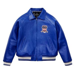 May include: A bright blue leather bomber jacket with a collared neckline and zip-up front. It has a patch on the chest with the text "AVIREX". The jacket features white and blue striped cuffs and hem, and is made of leather.