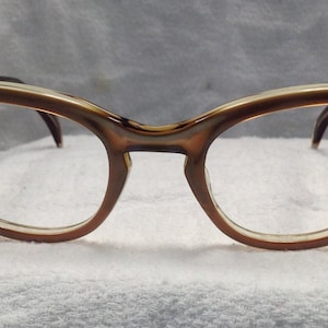May include: A pair of brown and beige cat-eye glasses with clear lenses.