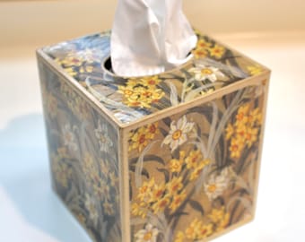 Könnte beinhalten: Ein quadratischer Taschentuchbox-Bezug mit einem Blumendesign mit gelben und weißen Narzissen auf braunem Hintergrund.