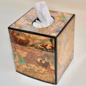 May include: Square tissue box featuring a vintage map design with a black trim. The box has a circular opening at the top for tissue dispensing. The map design includes illustrations and text, adding a classic aesthetic.