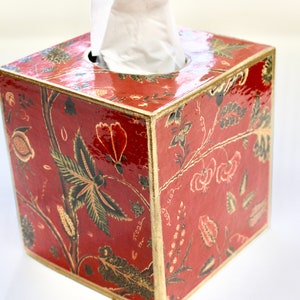 May include: Red tissue box cover with a gold trim and a floral pattern. The box is made of wood and has a glossy finish.