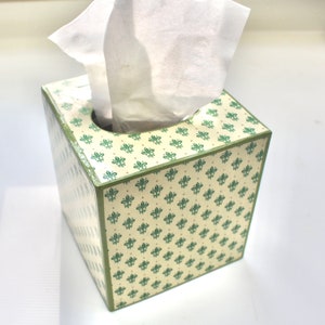 May include: A white tissue box cover with a green and white floral pattern. The box is made of wood and has a square shape.