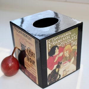 May include: Black wooden tissue box cover with a vintage design. The front features a black cat and the text "Chat Noir" with French text. The back features a vintage advertisement for "Compagnie Française des Chocolats et des Thés".