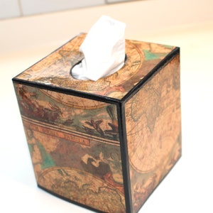 May include: Square tissue box with a vintage map design. The box is brown with black trim and a glossy finish. White tissues are visible at the top. The box has a classic, antique aesthetic.