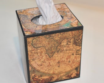 May include: A square tissue box with a vintage world map design. The box is brown with black trim and a circular opening at the top. White tissues are visible. The map features continents and nautical details.
