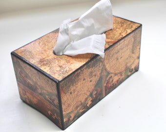 May include: A tissue box cover with a vintage world map design. The box is made of wood and has a black trim. The tissue box is empty and the top is open.