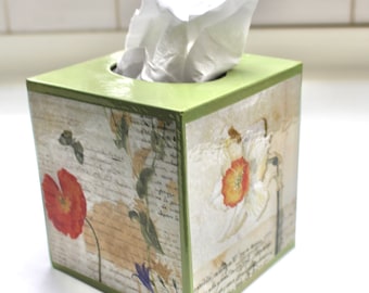 Könnte beinhalten: Ein grüner Taschentuchbox-Bezug mit einem Blumendesign mit roten Mohnblumen, weißen Narzissen und grünen Blättern auf cremefarbenem Hintergrund. Die Box ist aus Holz und hat eine glänzende Oberfläche.
