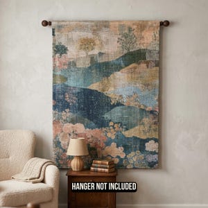 May include: A rectangular wall tapestry featuring a landscape scene with rolling hills, trees, and floral patterns in shades of navy blue, sage green, muted gold, and dusty pink. The textile hangs from a dark wooden rod. Text reads HANGER NOT INCLUDED.