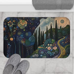 May include: A rectangular bath mat featuring a whimsical landscape design. The artwork depicts a winding path, trees, and flowers in shades of blue, green, and yellow. The mat is placed on a tiled floor, with a pair of gray slippers visible.