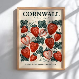 May include: A framed print featuring a cream-colored background with a pattern of red strawberries and green leaves. The print includes the text "CORNWALL" and "Cornish Strawberries and Cream."