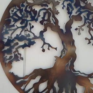 May include: A metal wall art piece depicting a tree with intricate branches and roots. The tree is cut out of metal and painted in shades of brown and blue.