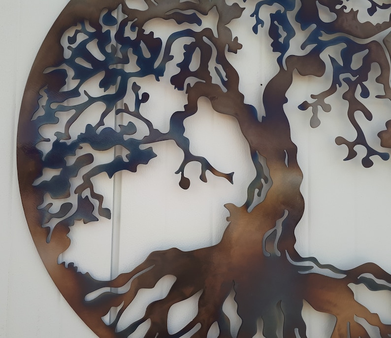May include: A metal wall art piece depicting a tree with intricate branches and roots. The tree is cut out of metal and painted in shades of brown and blue.