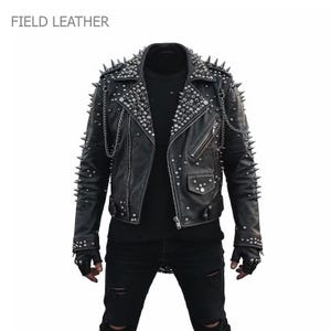 May include: Black leather jacket with silver spikes and studs. The jacket has a zipper closure, multiple pockets, and chain detailing. The text "FIELD LEATHER" is in the upper left corner.