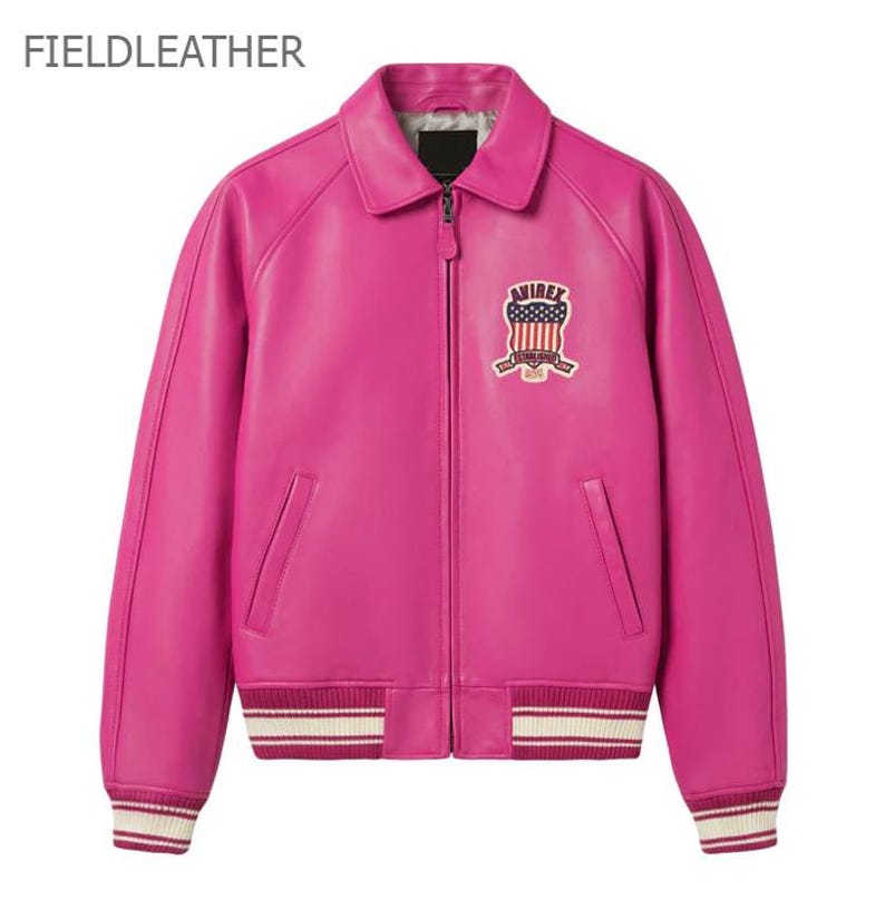 Puede incluir: Chaqueta de cuero rosa brillante de estilo bomber cl&aacute;sico. Cuello camisero, cierre de cremallera y parche en el pecho. Los pu&ntilde;os y el dobladillo tienen rayas blancas y crema. El texto "FIELDLEATHER" est&aacute; en la parte superior.