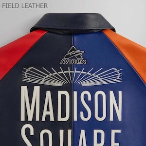 Puede incluir: Chaqueta de cuero con dise&ntilde;o de bloques de color en rojo, azul y naranja. La chaqueta tiene texto bordado en blanco que dice "MADISON SQUARE" y el logotipo "AVIREX". El cuello es azul marino y la etiqueta dice "FIELD LEATHER".