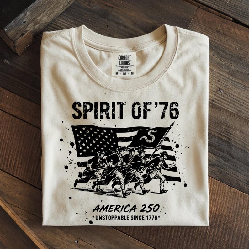 A cream Comfort Colors t-shirt featuring a black monochrome Spirit of 76 design.