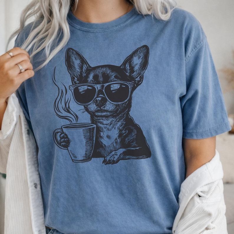 Puede incluir: Camiseta azul con un gr&aacute;fico negro de un chihuahua con gafas de sol y una taza de caf&eacute;. El perro est&aacute; representado con vapor saliendo de la taza. La camiseta tiene un corte holgado y cuello redondo.
