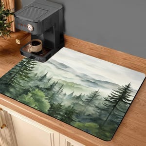 May include: A watercolor painting of a misty forest scene with a soft, muted color palette. The painting features a variety of trees and foliage, with a hazy background that suggests a distant mountain range. The painting is printed on a kitchen mat, which is perfect for adding a touch of nature to your kitchen.