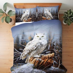 May include: A bedding set featuring a photographic print of a snowy owl perched on a tree stump in a winter landscape. The design includes a large duvet cover and two matching pillowcases, all displaying the same white owl with yellow eyes.