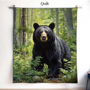 Pode incluir: Uma colcha retangular com uma estampa detalhada de um urso preto em pé em uma floresta verde exuberante. O urso tem pelo escuro e um focinho claro. O ambiente inclui árvores altas, folhagem verde e samambaias. A palavra Quilt está impressa no topo.