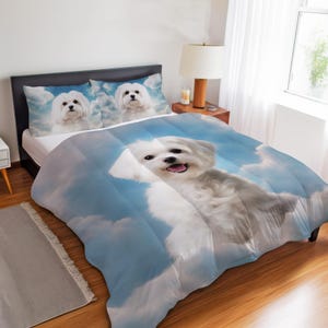 May include: A bedding set featuring a white Maltese dog with fluffy fur against a blue sky with white clouds. The set includes a comforter and two matching pillowcases, all displaying the same canine portrait with a bright, clear sky background.
