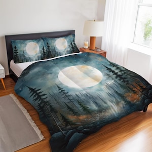 May include: A bedding set featuring a duvet cover and two pillowcases with a dark blue and teal forest landscape print. The design depicts a large, glowing full moon centred in a starry night sky above silhouettes of tall pine trees and rocks.