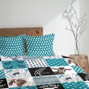 Peut inclure: Une courtepointe patchwork et deux taies d'oreiller turquoise avec des empreintes de sabots de chèvre blanches. La courtepointe présente divers carrés sur le thème des chèvres avec des images de chèvres, du texte et des motifs.