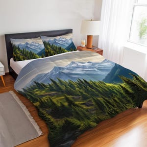 May include: A bed set with a mountain landscape design. The bedding includes a duvet cover and two pillowcases, all displaying a scenic view of snow-capped mountains and evergreen trees. The colour palette includes shades of green, blue, and white.