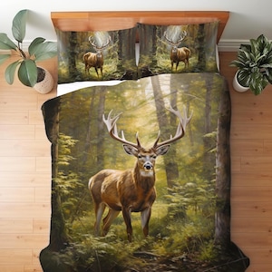 May include: A bedding set featuring a duvet cover and two pillowcases with a printed forest scene. The design displays a large brown deer with antlers standing in a sunlit woodland area with green foliage and tall trees throughout the fabric.