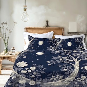 May include: A dark navy blue duvet cover and two matching pillowcases featuring a white botanical print of a large tree, various flowers, and a full moon against a starry night sky. The bedding set is displayed on a bed with white pillows.
