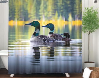 May include: A shower curtain featuring a high-resolution print of two adult loons and one small loon chick swimming on a calm lake. The birds have black and white patterned plumage with dark heads, set against a blurred background of yellow trees.